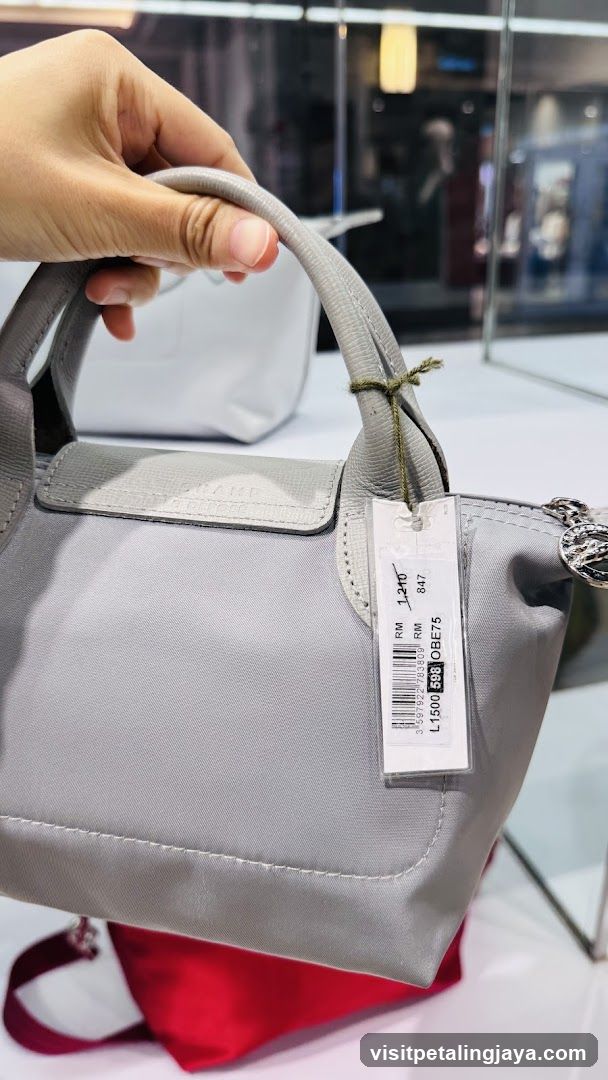 Hand holding a gray handbag