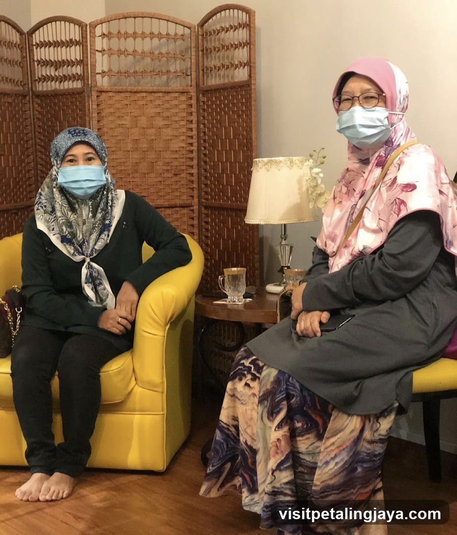 Two women wearing face masks and hijabs sitting in chairs