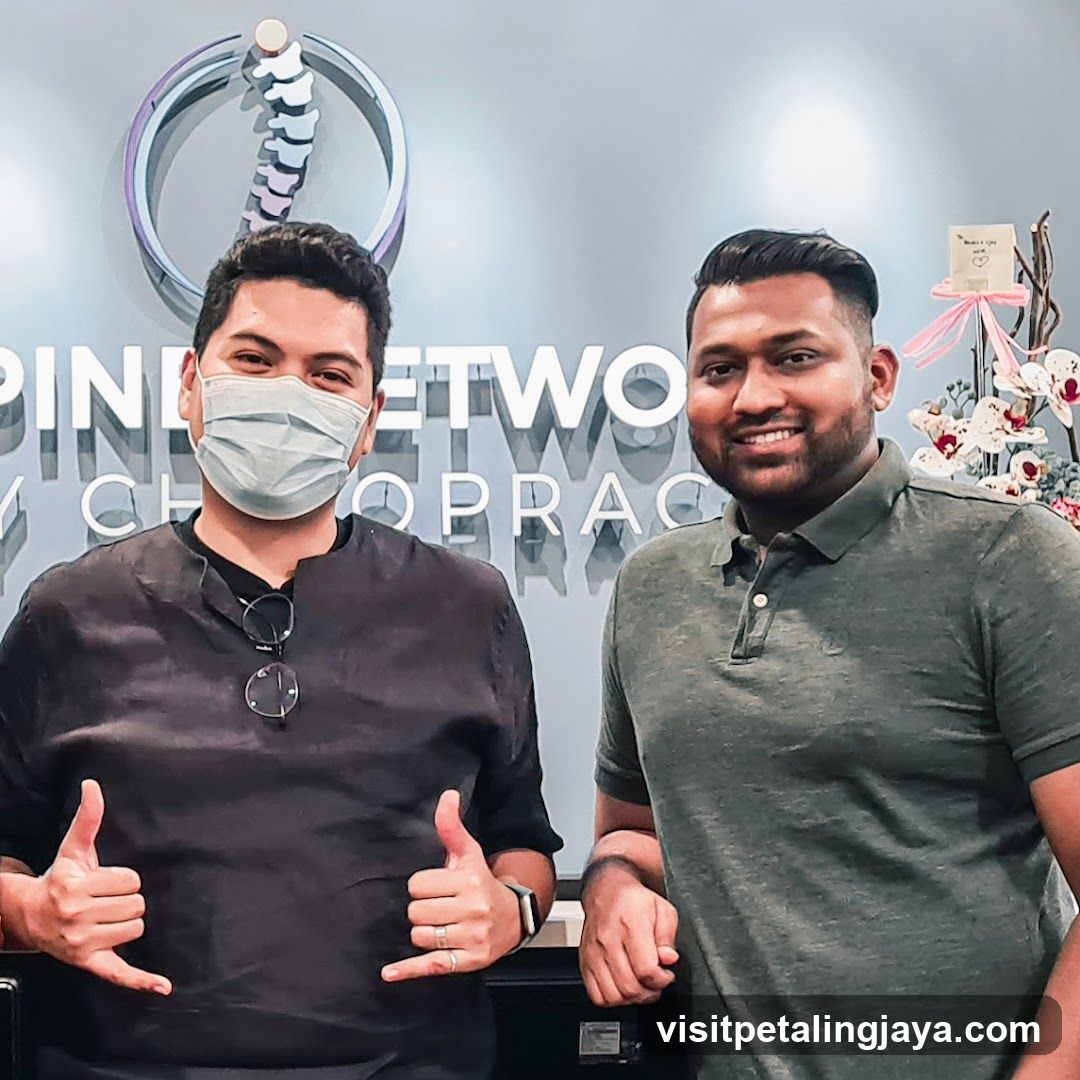 Two men in front of a chiropractic clinic sign