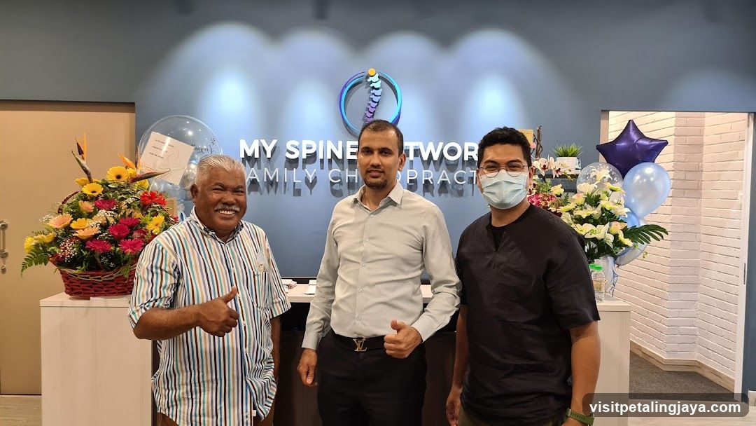 Three men posing in front of a chiropractic clinic sign