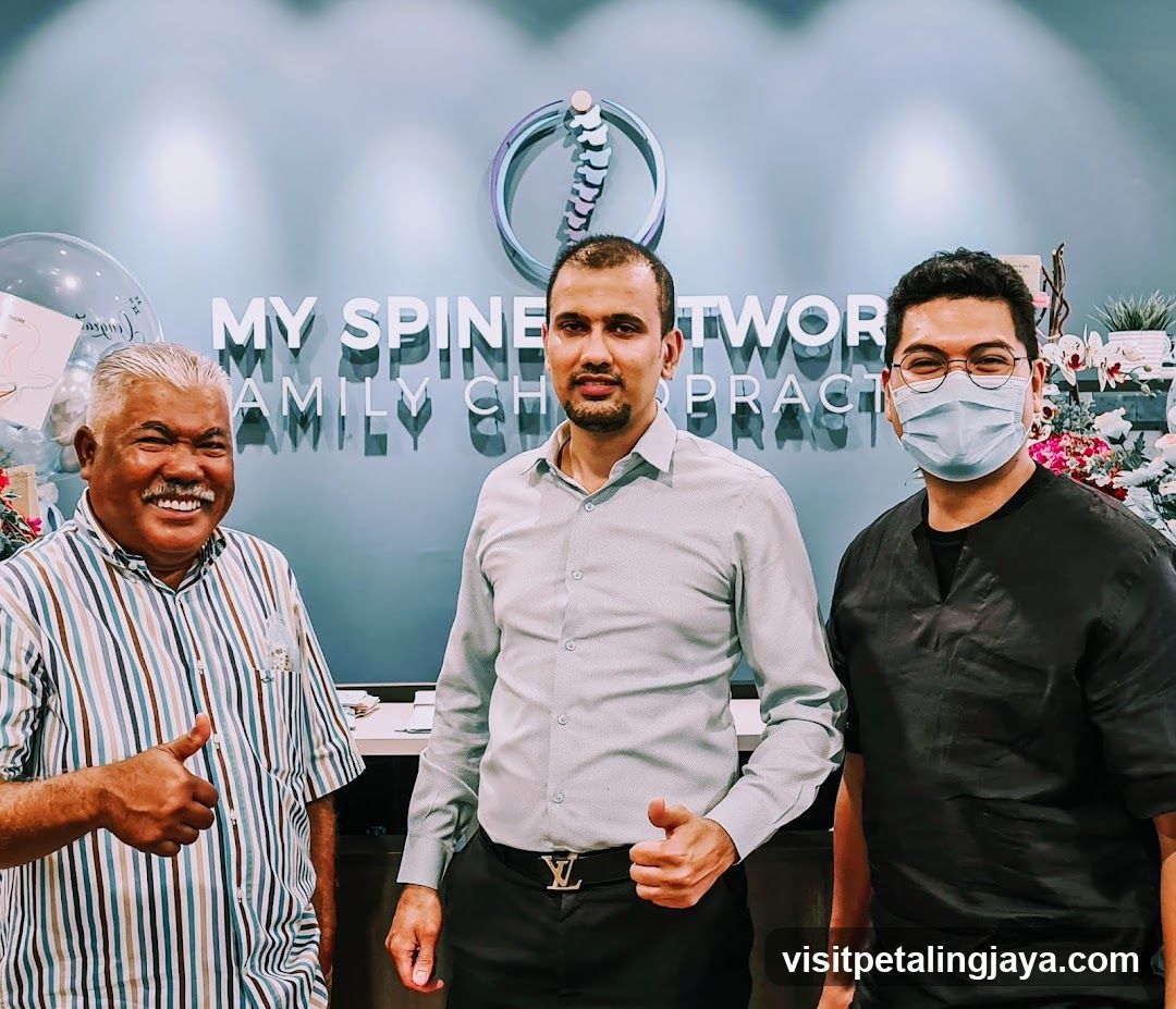 Three men posing in front of a clinic sign