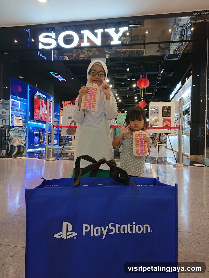 Two children with Dunkin' Donuts boxes in front of a Sony store