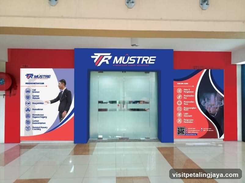 The image shows the entrance to a business called TR Mustre. The entrance features double glass doors framed by a blue structure with the TR Mustre logo prominently displayed above. To the left of the entrance is a large poster with the TR Mustre logo and a list of services including