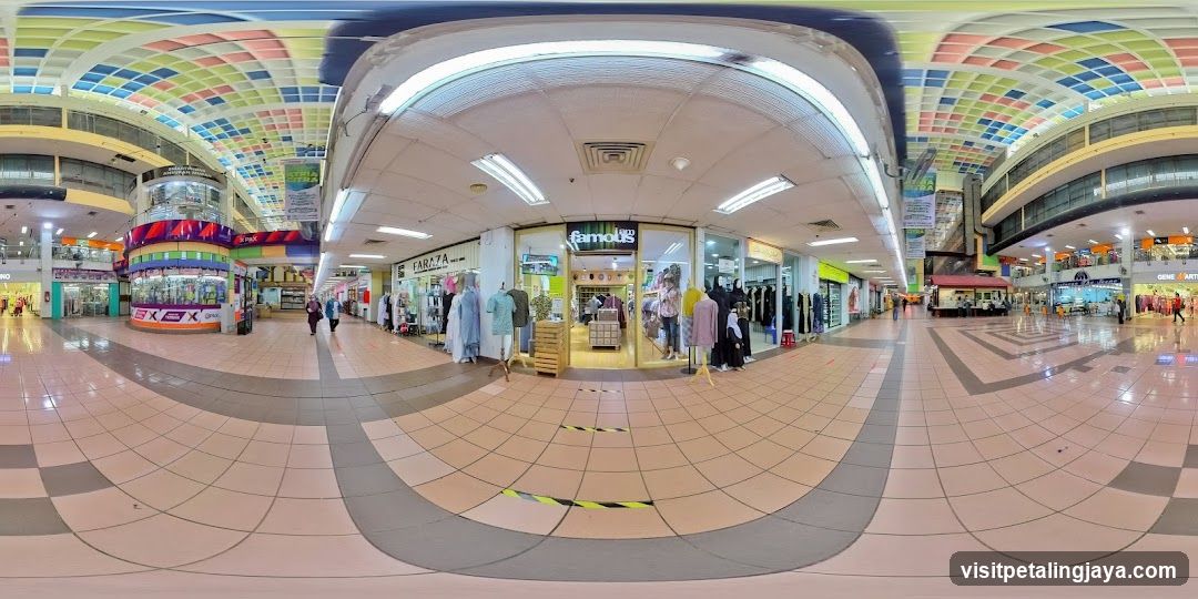Indoor shopping mall with various stores and colorful ceiling