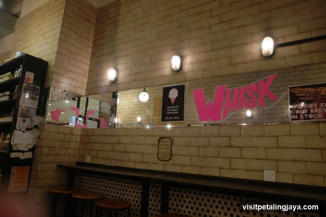 Interior of a cafe with tiled walls and a prominent "WHISK" logo.