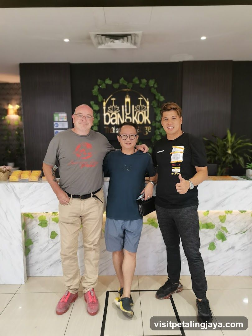 Three men posing in front of a massage parlor sign