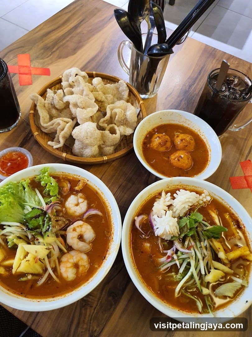 Two bowls of laksa with shrimp and squid, fish crackers, and drinks