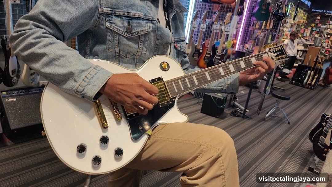 Person playing a white electric guitar in a music store
