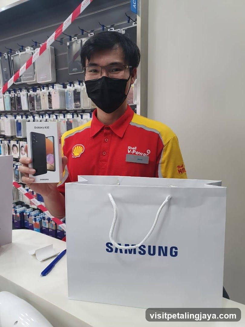 Employee holding a Samsung Galaxy A32 box and a Samsung shopping bag