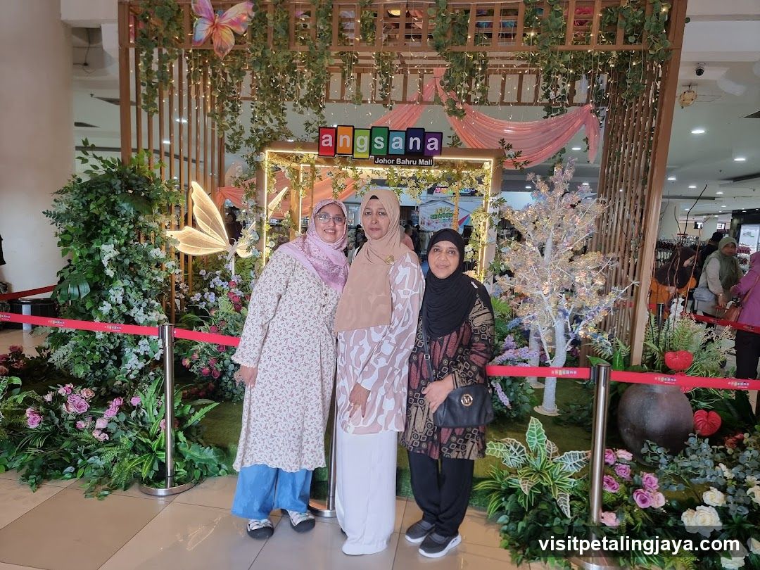 Three women posing in front of a decorative display
