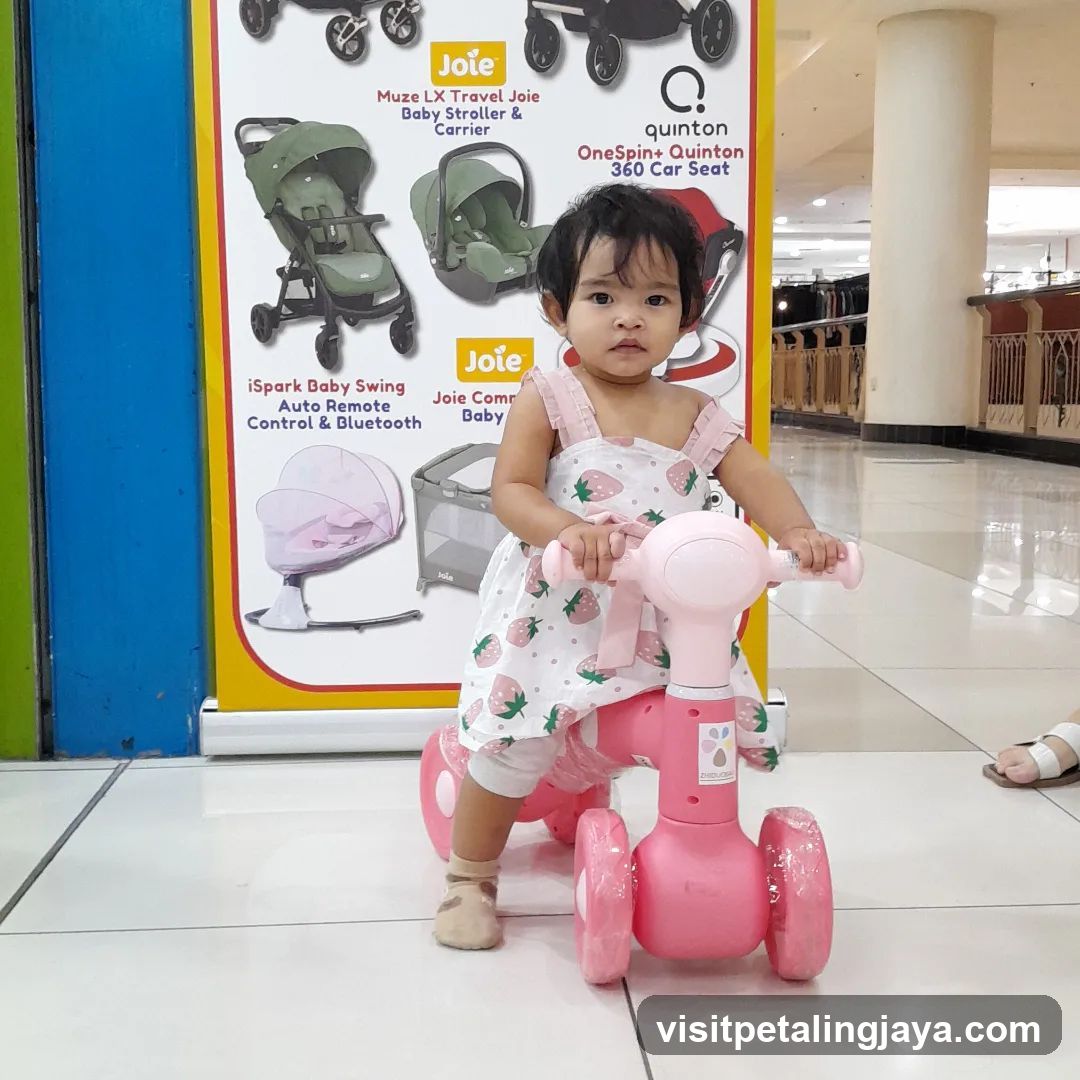 Child on a pink ride-on toy in front of a display of baby gear