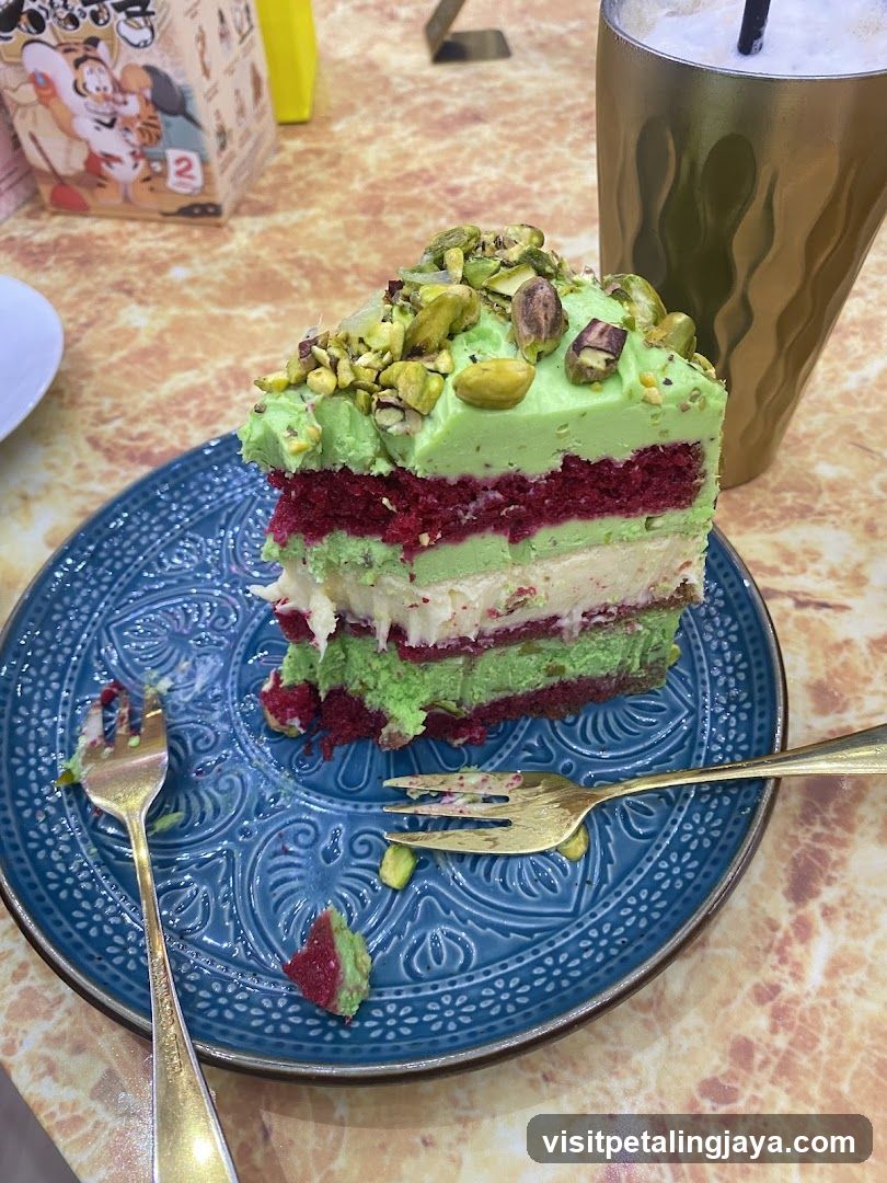 Slice of layered green and red cake with pistachio topping