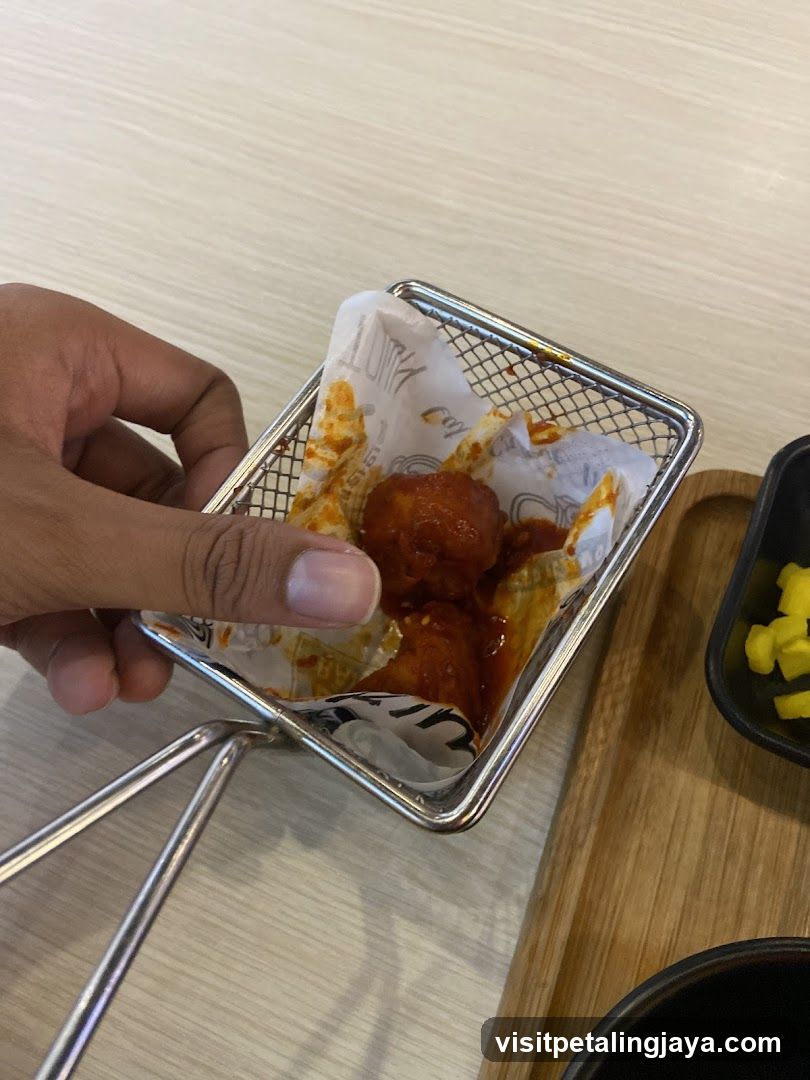 Hand holding fried chicken in a metal basket