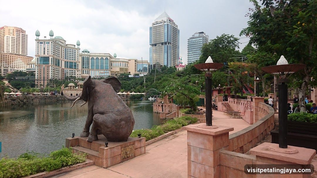 Elephant statue by a lake with city buildings in the background