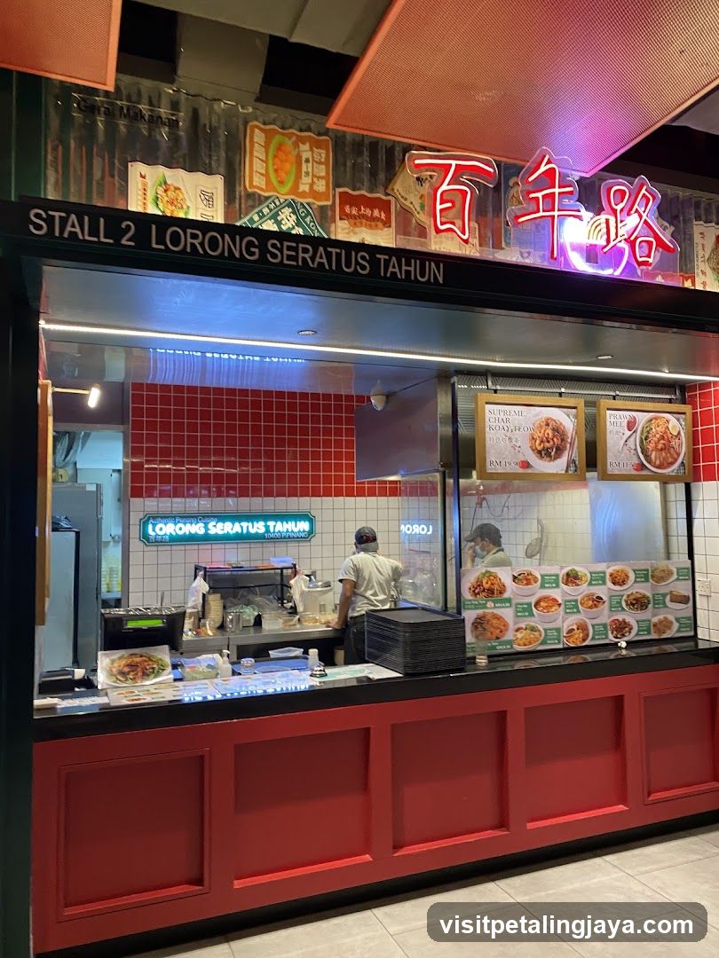 A food stall with red and white tiled walls, neon signage reading '百年路' (Bai Nian Lu), and a menu board displaying various dishes behind glass.