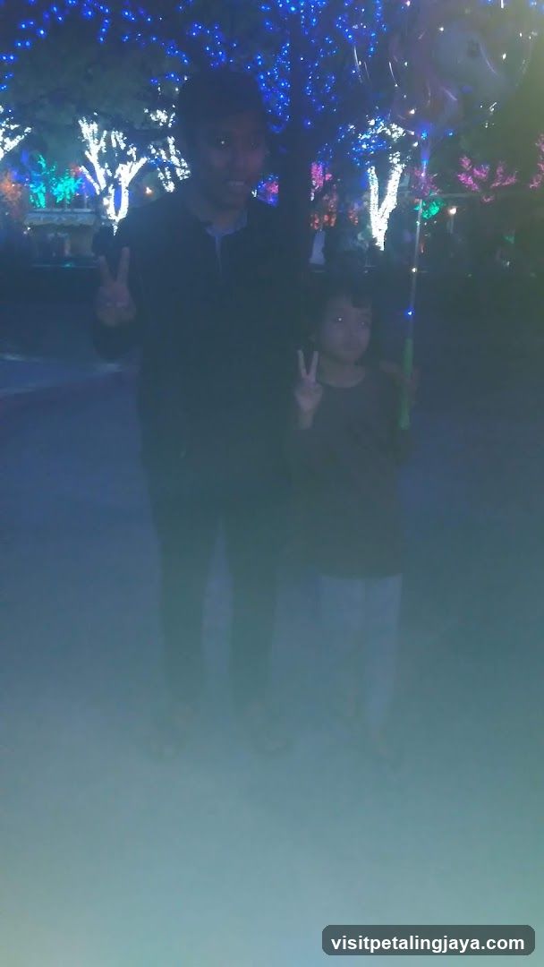 Two people posing with peace signs in front of illuminated trees