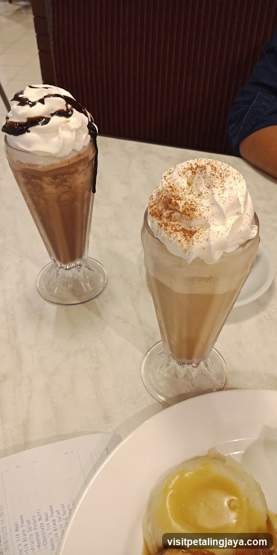 Two milkshakes and dessert on a table