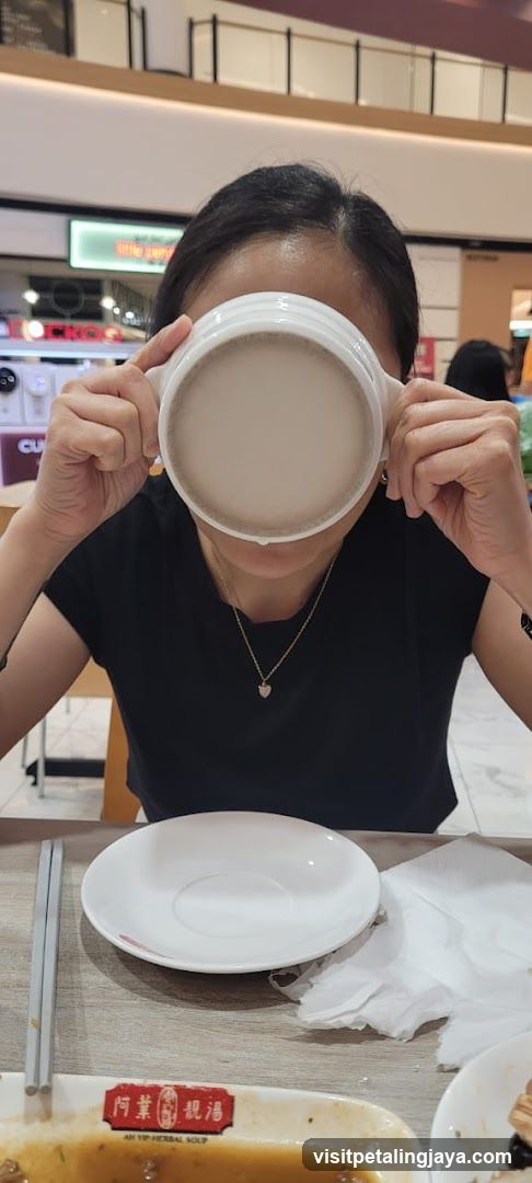 Person drinking soup in a mall food court