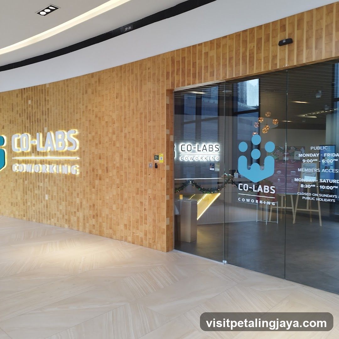 Photo of the physical storefront facade featuring a wooden-paneled wall with illuminated 'CO-LABS COWORKING' signage on the left and glass doors displaying the same logo and operating hours.