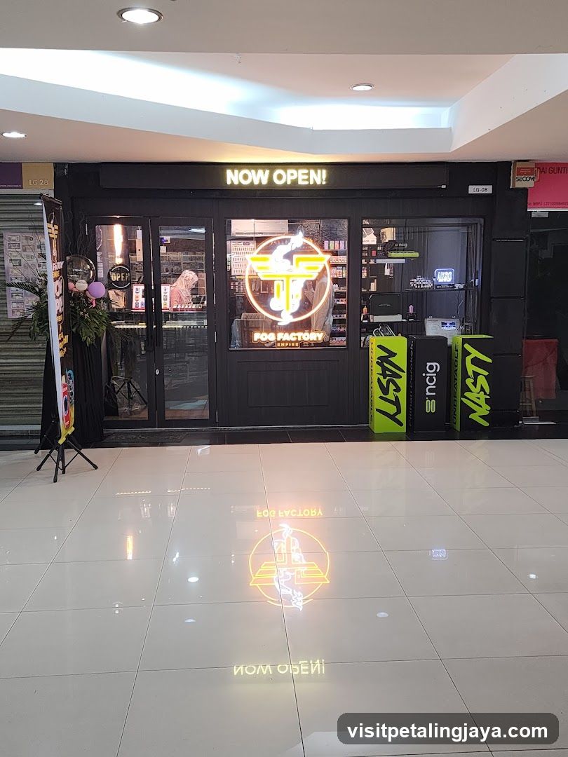 A shop with a black facade and illuminated signage reading 'NOW OPEN!' above the entrance. The storefront features glass doors and windows displaying interior shelves stocked with products. A neon logo is visible on the window, along with promotional banners outside.