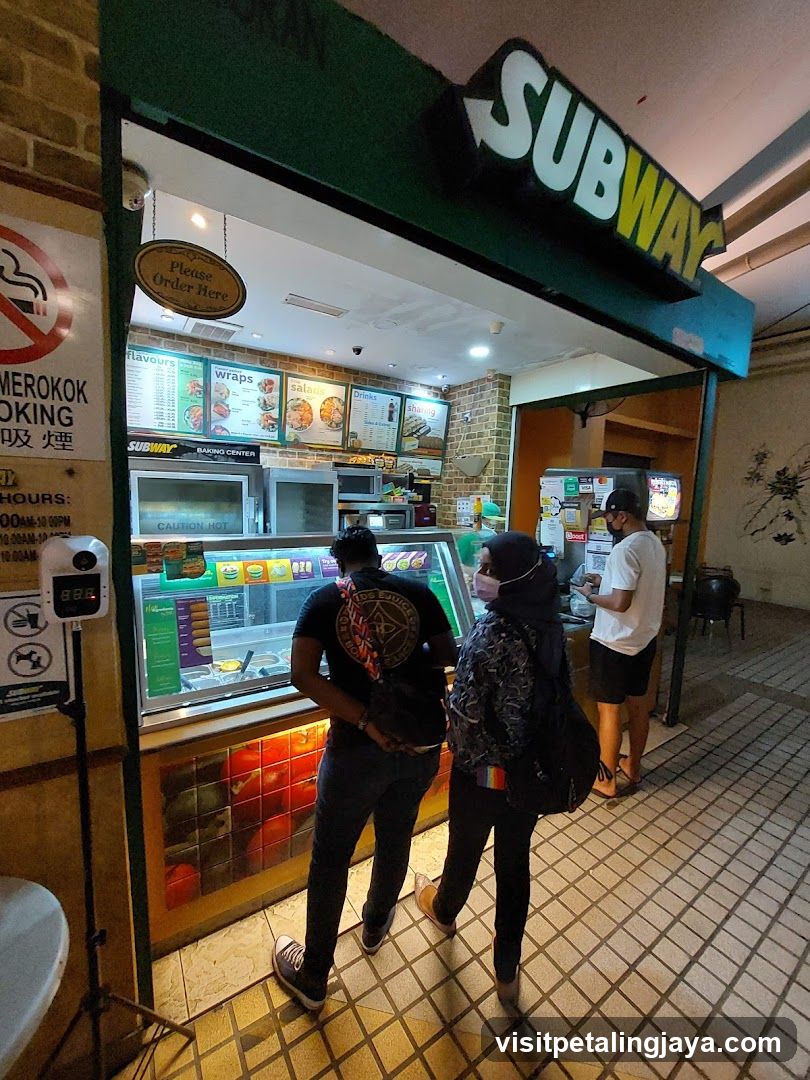 A Subway sandwich shop entrance with visible signage and customers ordering.