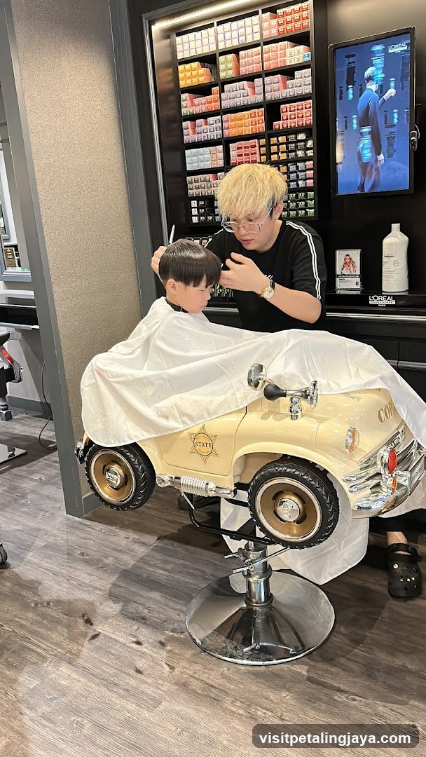 Barber cutting kid's hair in car chair
