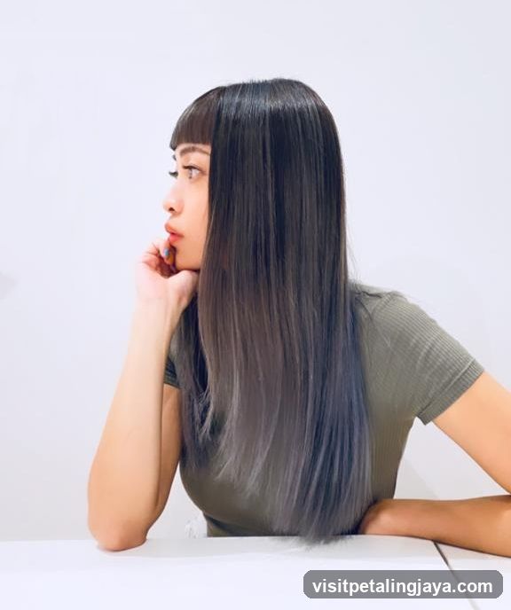 Woman with long dark hair and bangs sitting at a table