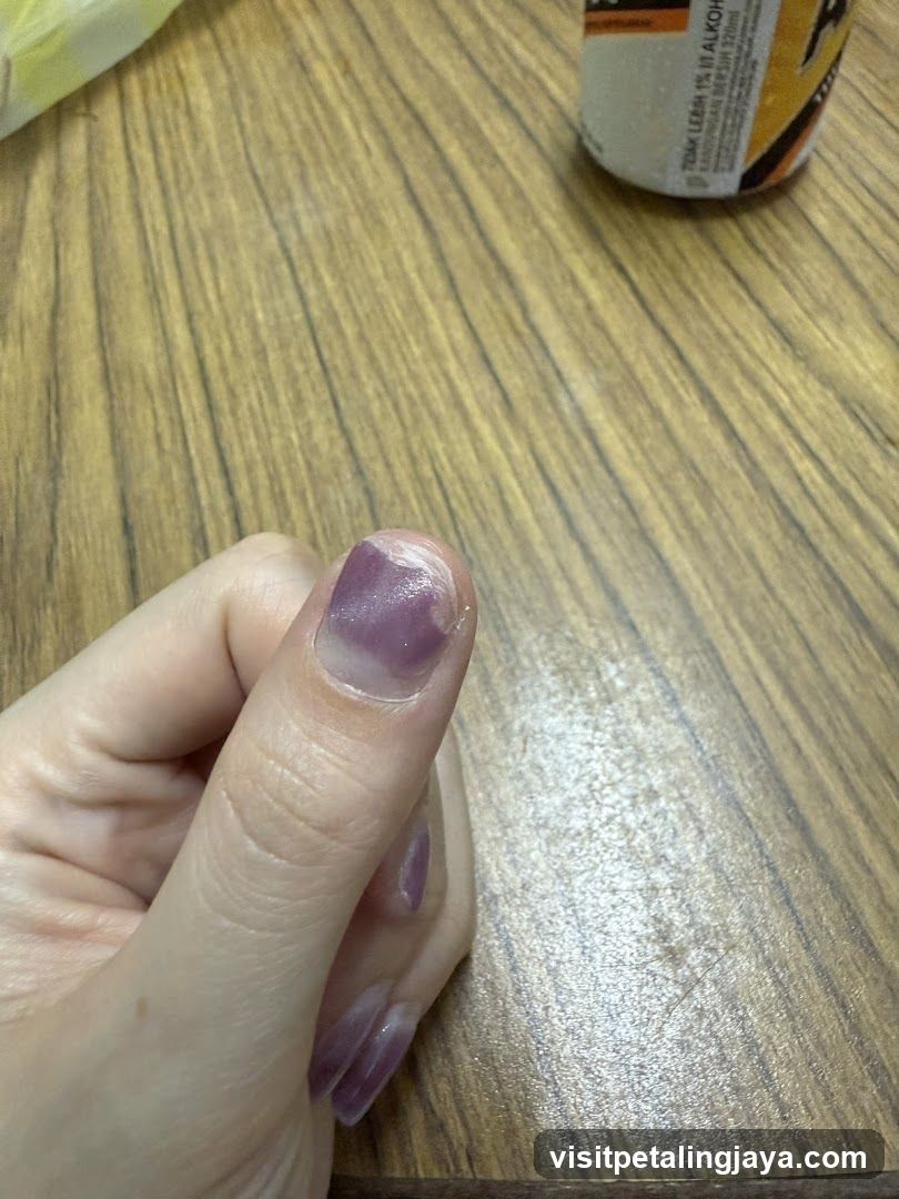 Hand with purple nail polish on wooden table
