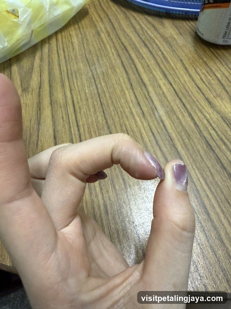 Hand with purple nail polish on wooden table