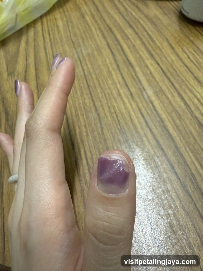 Hand with purple nail polish on wooden table