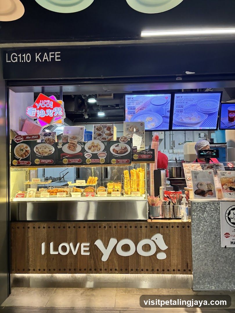 A food stall with a wooden facade displaying 'I LOVE yoo!' and various menu boards above the counter showing dishes like rice bowls and fried items.
