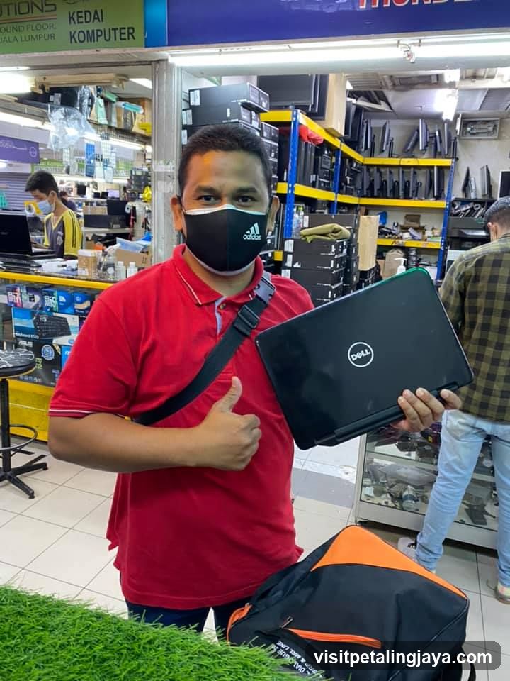 Man holding laptop in electronics shop