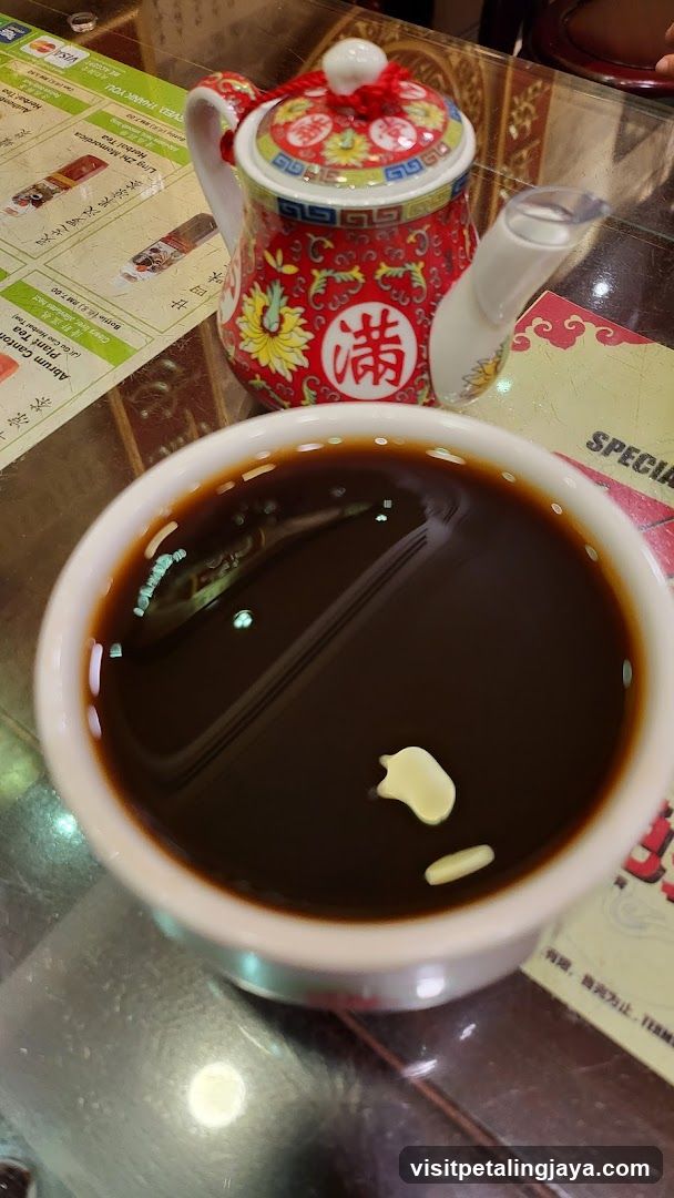 Bowl of dark liquid with garnish and decorative teapot