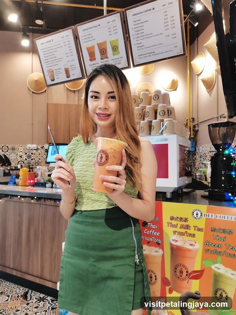 Woman holding Thai milk tea at Dee Coffee shop