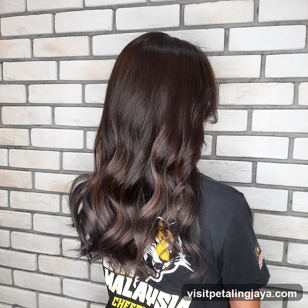 Person with long wavy hair against brick wall