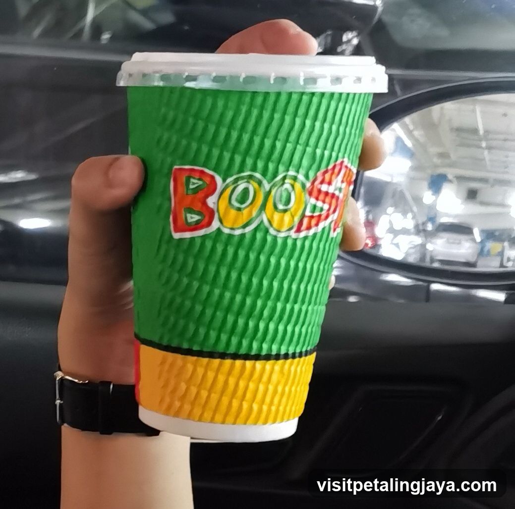 Hand holding a green and yellow cup with 'BOOST' logo