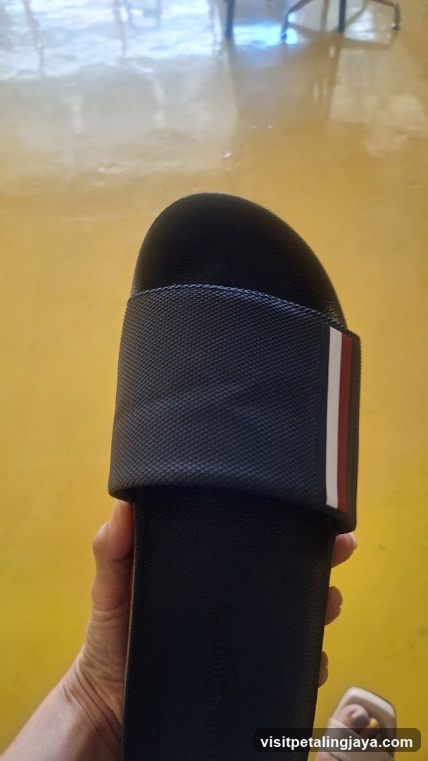 Hand holding a black slide sandal