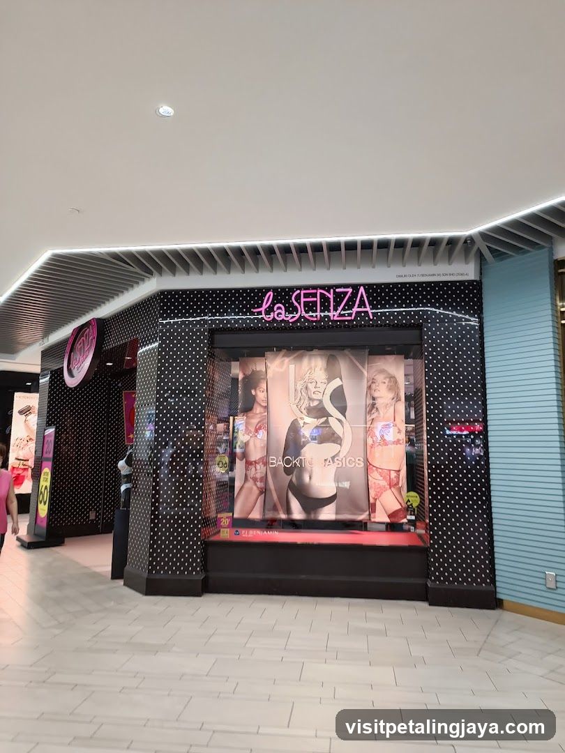 The image shows the exterior storefront of a La Senza store, featuring a black facade with white polka dots and pink neon lettering above the entrance. Large posters in the window display lingerie models.