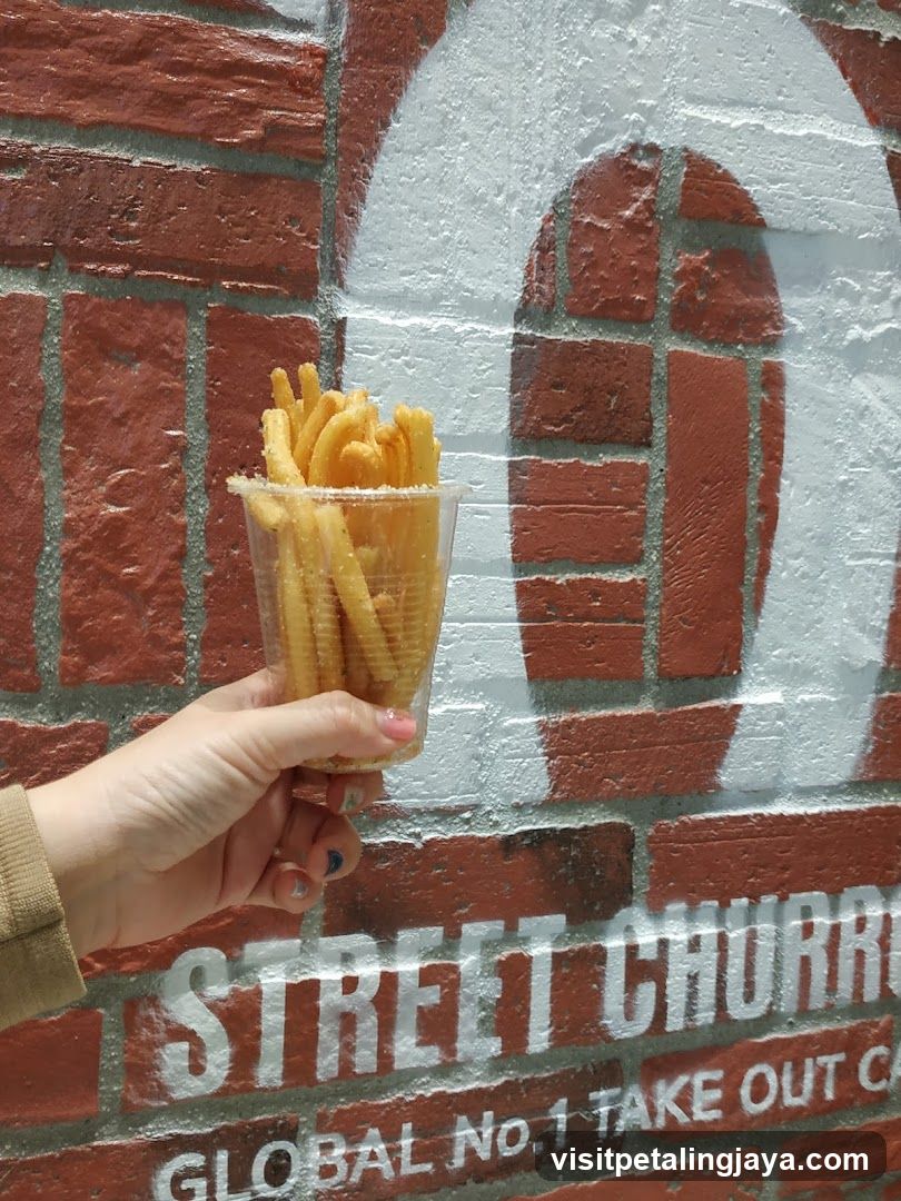 Hand holding fries in front of brick wall with signage