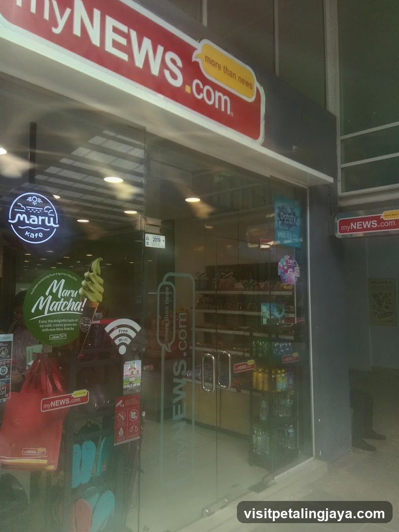 Photo of the exterior entrance of a myNEWS.com store, featuring glass doors with signage including 'more than news' and 'maru kare', along with promotional stickers inside.