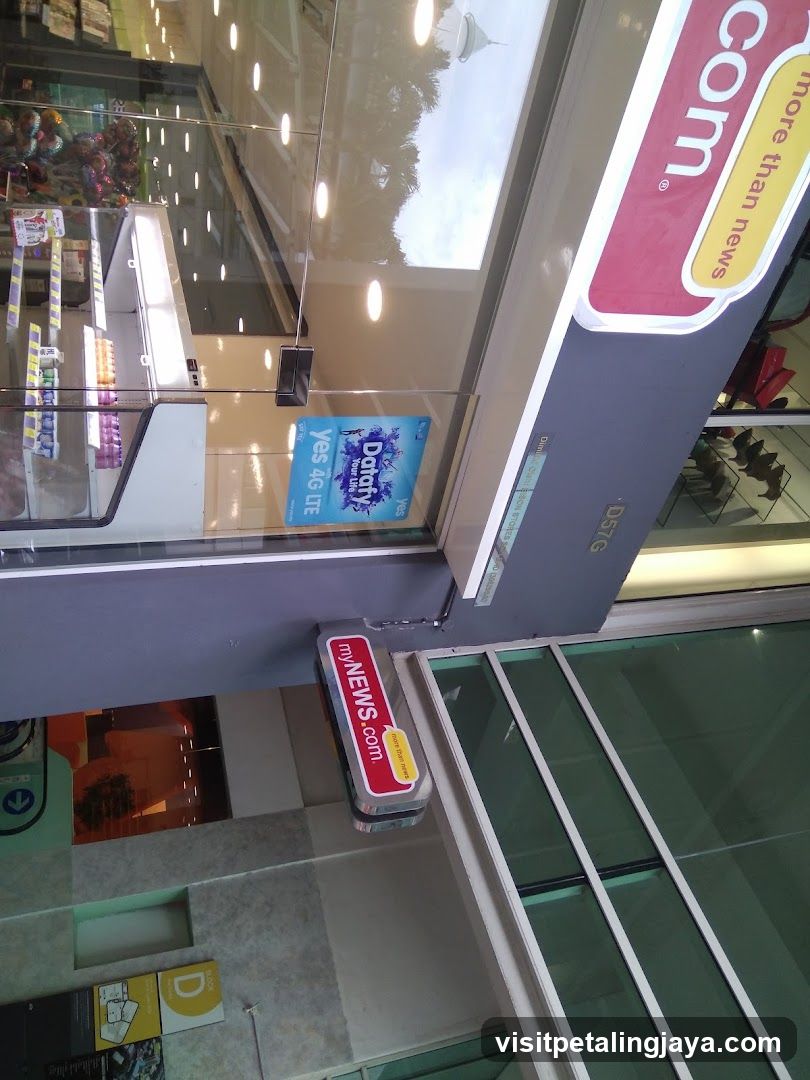 Photo of a shop entrance showing glass doors and signage including 'myNEWS.com' on a red sign attached to the door frame, and partial branding visible above.