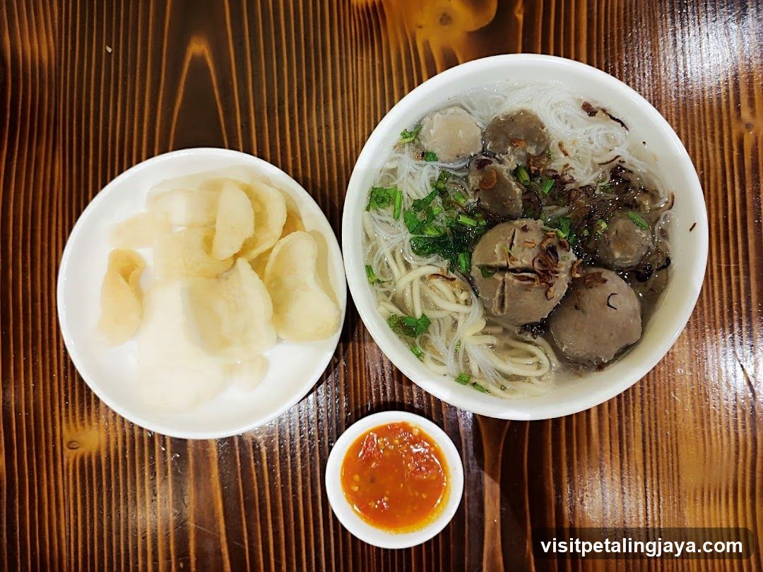 Bowl of Noodle Soup with Meatballs and Chips