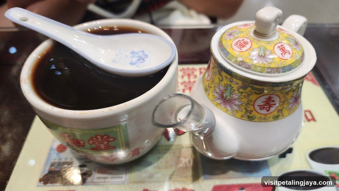 Cup of dark liquid with teapot
