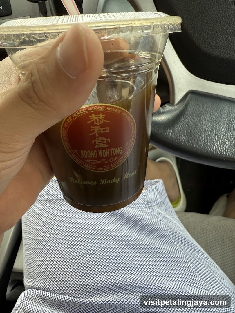 Hand holding a cup of iced tea from Koong Woh Tong