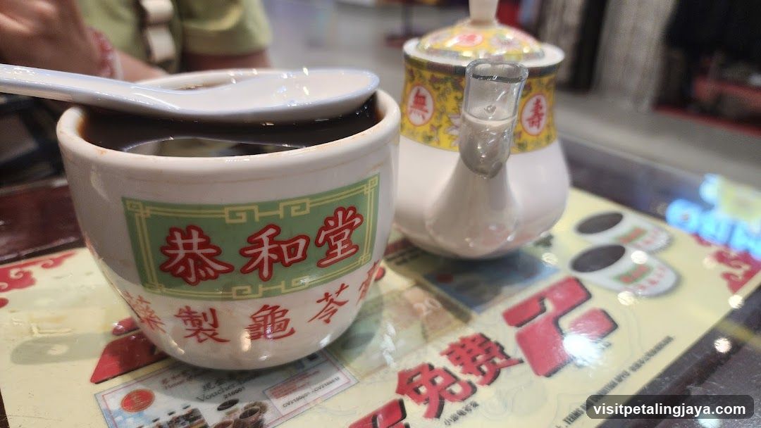 Bowl of dark soup with spoon and teapot on table mat
