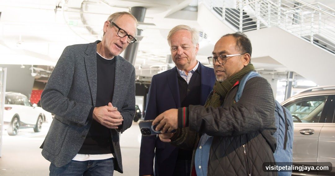 Three men in a car showroom