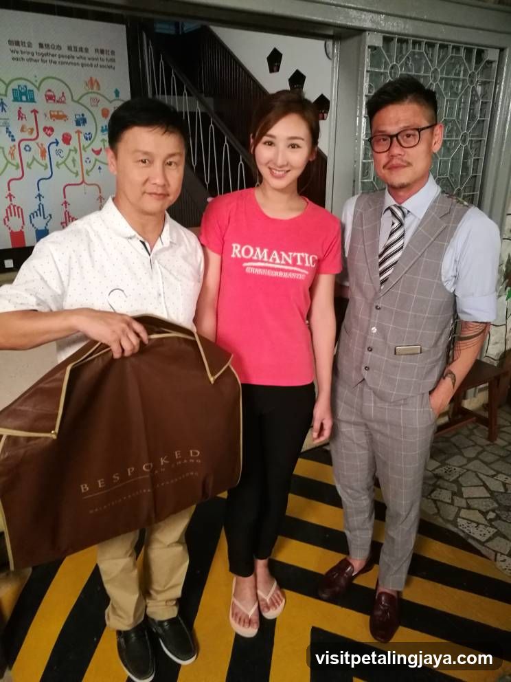 Three people posing indoors with a garment bag