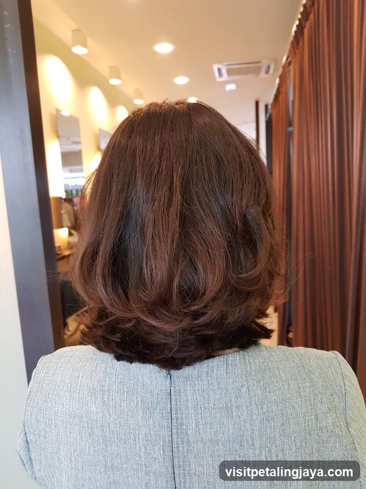 Back of a person with styled brown hair in a salon