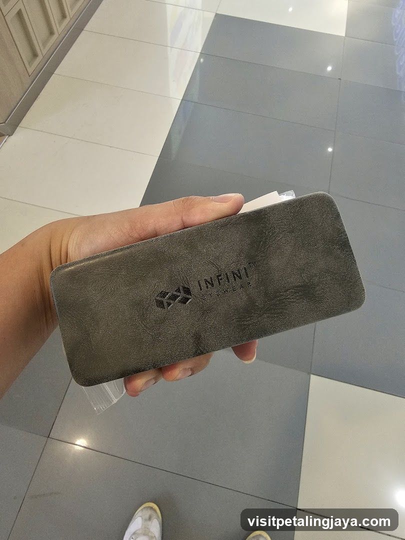 Hand holding a dark grey case with logo