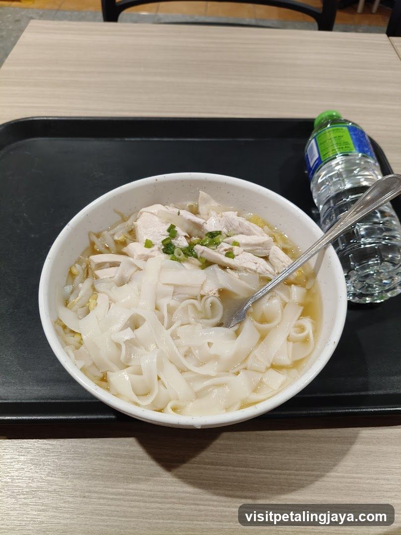 Bowl of noodles with chicken and water bottle on tray